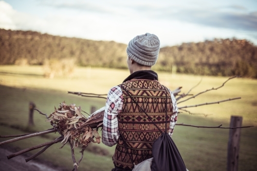 Person carrying sticks kindling for fire - Australian Stock Image