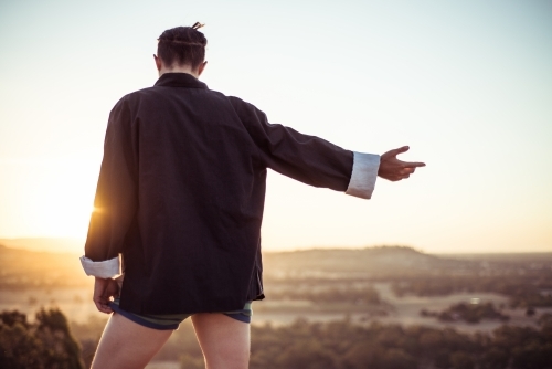 Person doing Ti Chi outdoors in rural area with sun setting in distance - Australian Stock Image