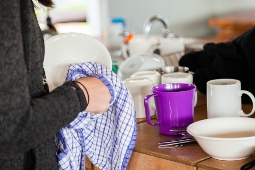 Person drying up dishes beside sink at park campground - Australian Stock Image
