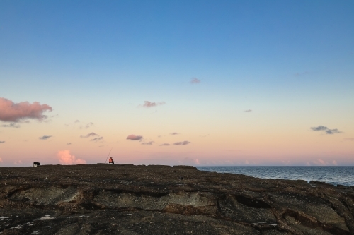Person fishing from rocks at Norah Head, New South Wales Australia - Australian Stock Image