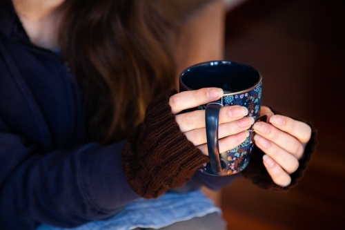 Person holding cup of chai tea in winter to keep warm - Australian Stock Image