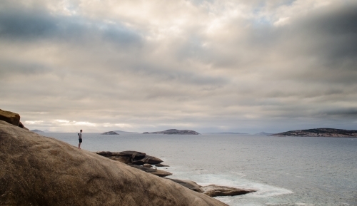 Person on rocks looking out over salmon beach - Australian Stock Image