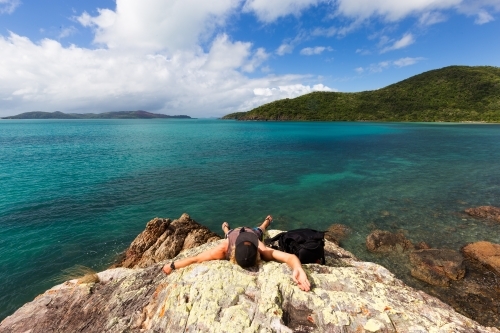 Person relaxing at a remote tropical, rocky beach in the Whitsundays