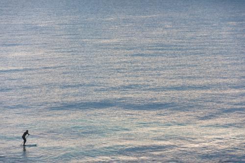 Person Riding on Stand up Paddleboard in Distance - Australian Stock Image