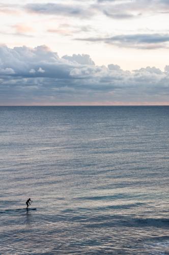 Person Riding on Stand up Paddleboard with Ocean and Horizon - Australian Stock Image
