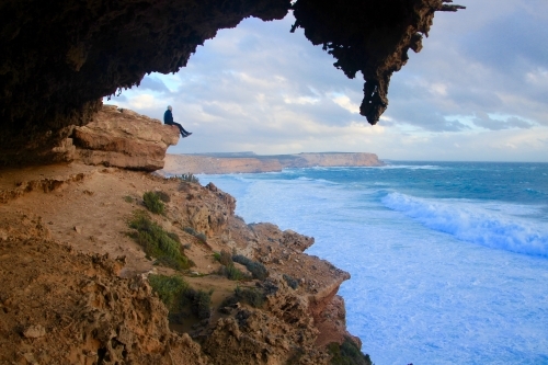 Person sitting on a cliff watching coming storm - Australian Stock Image