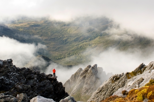 Person standing on a cliff in a misty mountain range