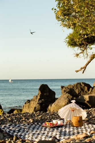 Picnic mat set up with an umbrella along the seaside - Australian Stock Image