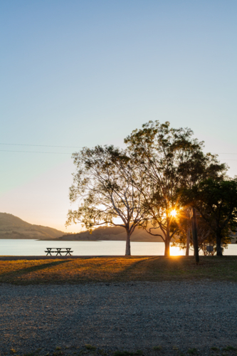Picnic table at campground in Australia with lake waters and hills in the distance - Australian Stock Image