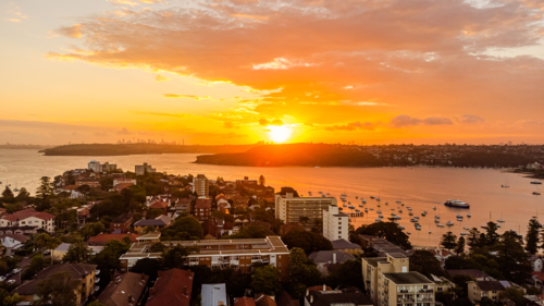 picturesque coastal bay with boats at sunset - Australian Stock Image
