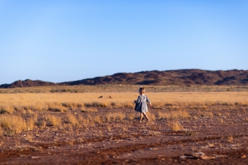 pilbara landscape with blue sky and small child in mid ground - Australian Stock Image