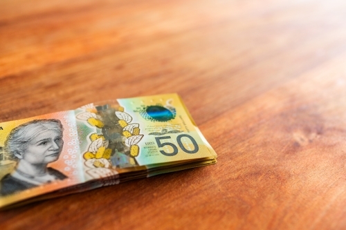 Pile of cash in fifties on wooden table with copy space - Australian Stock Image