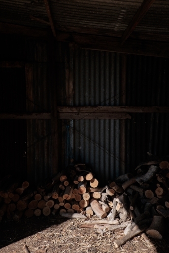 Pile of firewood in sunlit shed - Australian Stock Image
