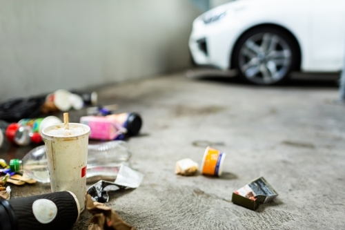 Pile of trash in corner of carpark, dirty takeaway cups and plastic bottle with cigarette packaging - Australian Stock Image