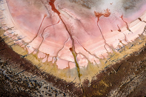 Pink salt lake patterns with cracked textures and radiating channels - Australian Stock Image