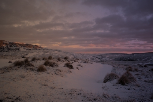 Pink sunrise over snow covered hills