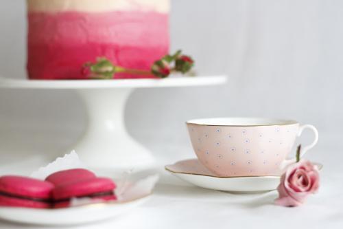 Pink tea cup beside macaron and cake - Australian Stock Image