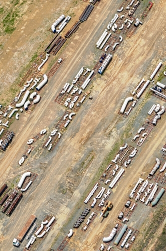 Pipes and industrial construction parts stocked on the ground for a liquefied natural gas plant - Australian Stock Image