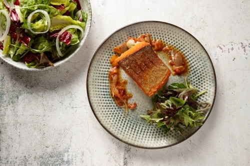 Plate of fish with bowl of salad on the side - Australian Stock Image