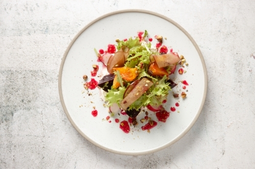 Plate of fresh salad of lettuce, beetroot, radish, stone fruit and vinaigrette - from above - Australian Stock Image