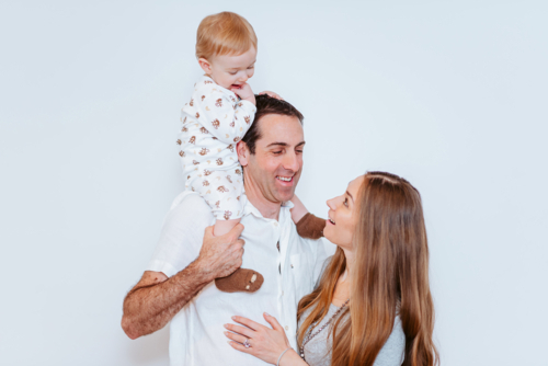 playful parents and their son sharing a parenthood moment on a white background - Australian Stock Image