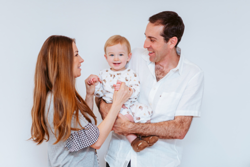 Playful young boy with his mid-aged parents, taken indoors on a white background - Australian Stock Image