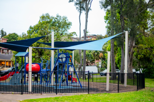 playground equipment in a vibrant park, on a sunny day under shade. - Australian Stock Image