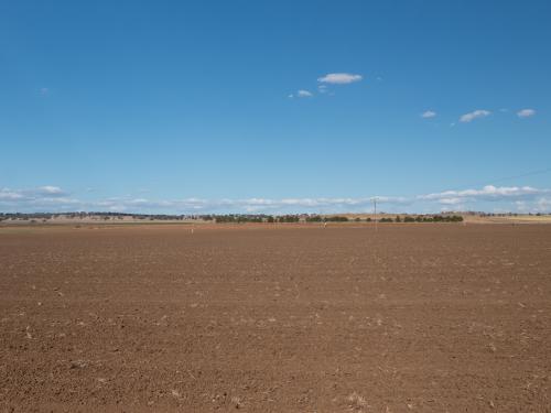 Ploughed paddock with brown soil and blue sky - Australian Stock Image