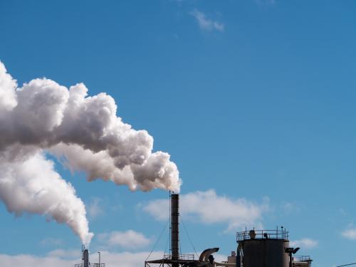 Plumes of steam rising from industrial chimneys into a blue sky - Australian Stock Image