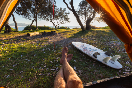 Point of view from a tent of man relaxing during crisp morning on a surf hike in Australia - Australian Stock Image