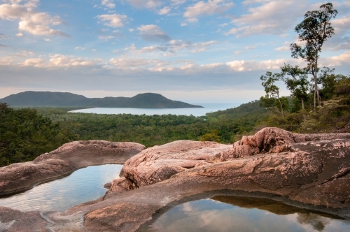 Pools in granite above Zoe Falls with views of Hinchinbrook Island in the background - Australian Stock Image