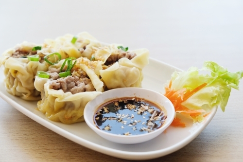 Pork dumpling; dim sum on white plate - Australian Stock Image