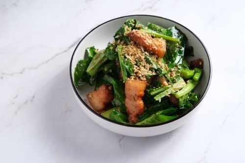 Pork stir-fry with green leafy vegetables served in a bowl - Australian Stock Image