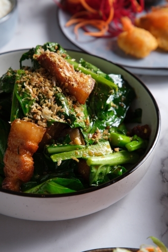 Pork stir-fry with green leafy vegetables served in a bowl. - Australian Stock Image