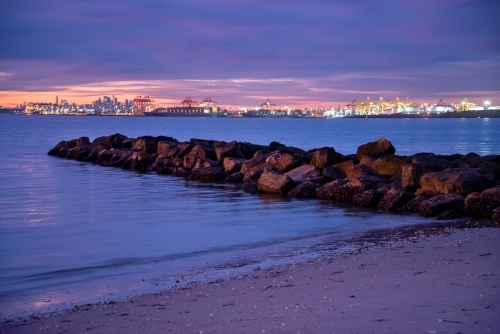 Port Botany at dusk with beach and rock groyne in foreground