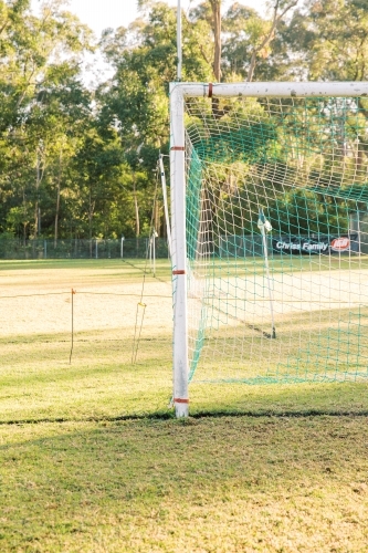 Portrait and a half shot of a soccer goal post with a net on a green big field - Australian Stock Image
