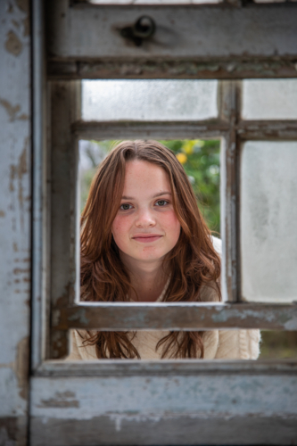 Portrait of a female looking through an old window - Australian Stock Image