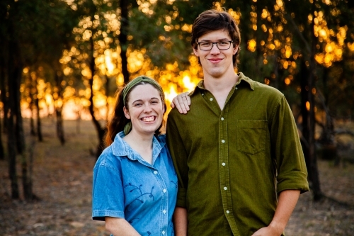 Portrait of a happy couple smiling at sunset with golden bokeh light - Australian Stock Image