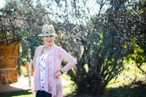 Portrait of a happy senior woman in a hat outside in winter garden - Australian Stock Image
