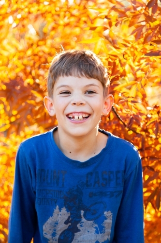 Portrait of a happy young boy laughing in autumn - Australian Stock Image