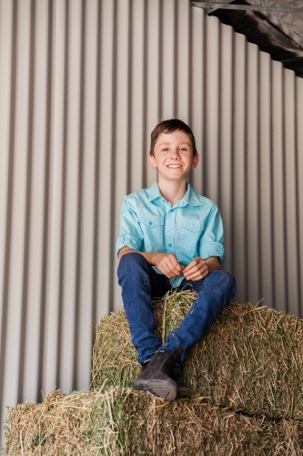Portrait of a happy young boy on hay bales in a shed