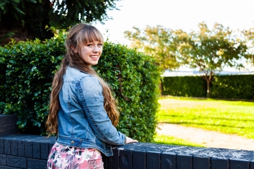 Portrait of a happy young woman leaning on a wall - Australian Stock Image