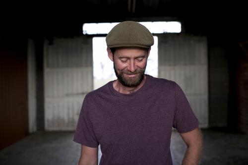 Portrait of a man wearing a hat with background of a dimly lit shed - Australian Stock Image