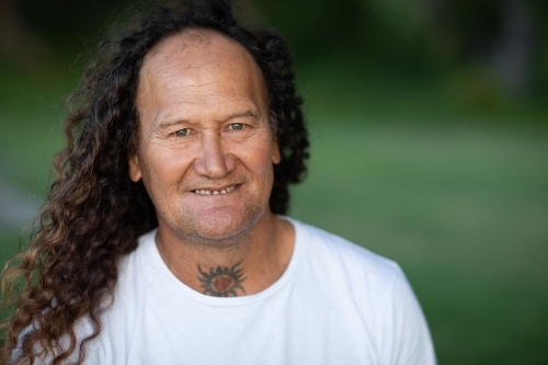 Portrait of a man with long curly hair smiling - Australian Stock Image