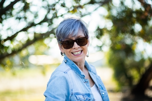 portrait of a senior woman in the garden wearing sunglasses - Australian Stock Image