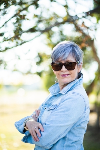 portrait of a senior woman in the garden wearing sunglasses - Australian Stock Image