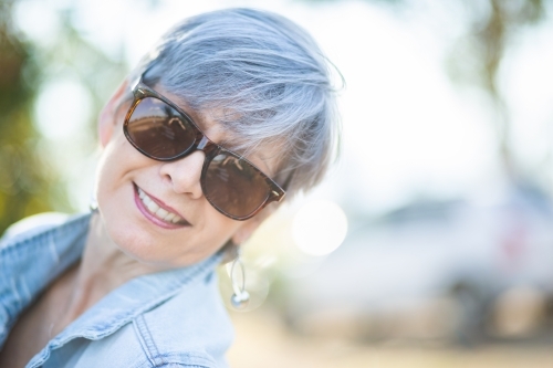 portrait of a senior woman in the garden wearing sunglasses - Australian Stock Image