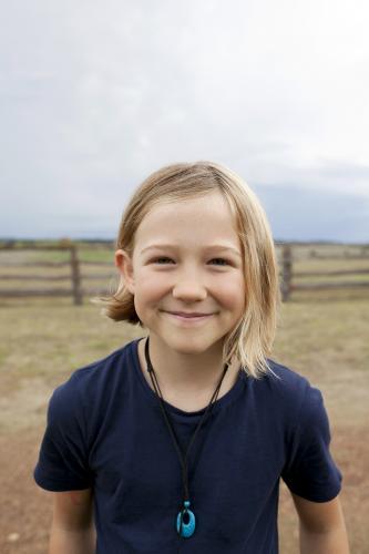 Portrait of a smiling blonde girl standing outside on farm - Australian Stock Image