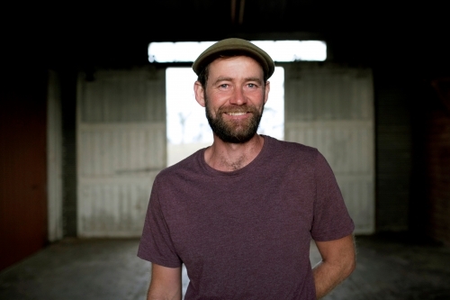Portrait of a smiling man with background of a dimly lit shed - Australian Stock Image