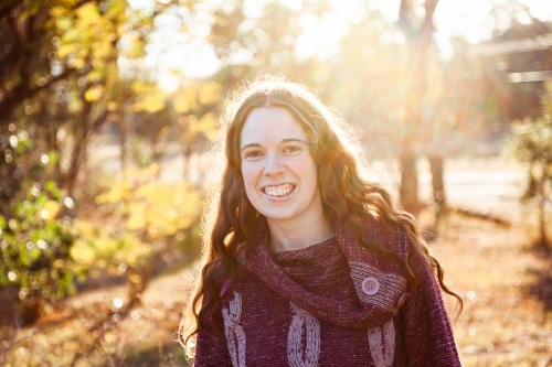 Portrait of a smiling young woman backlit by warm winter light - Australian Stock Image